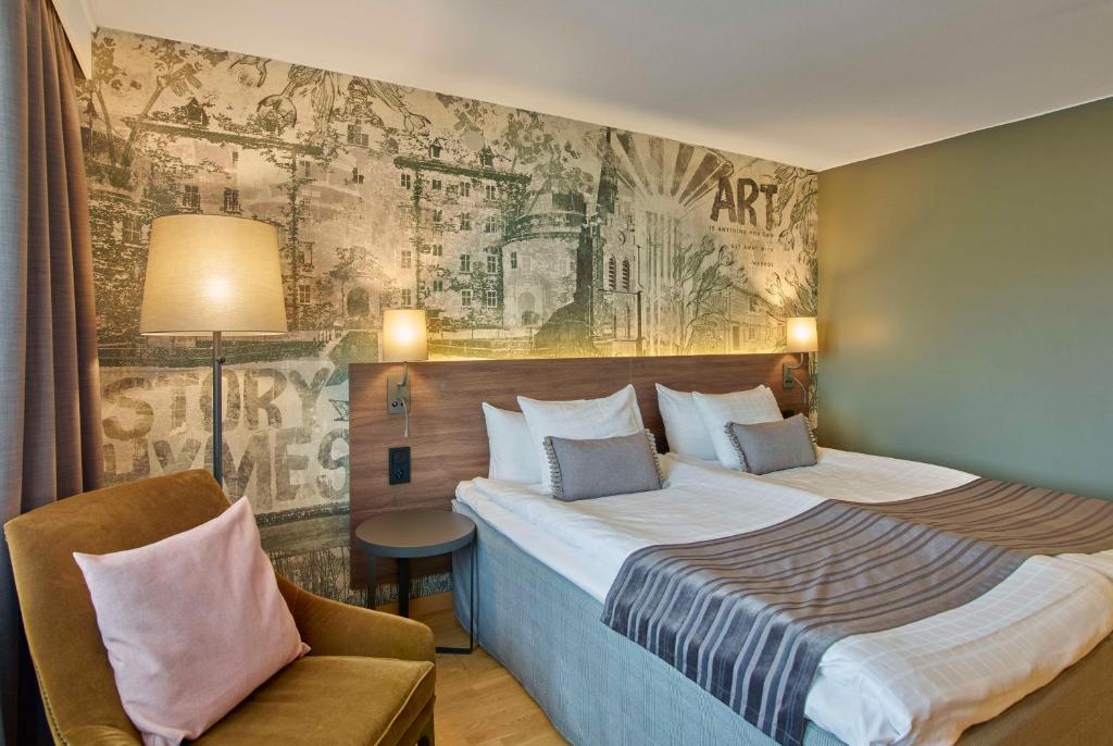 um quarto de hotel com uma cama grande e uma cadeira em Scandic Grand Hotel em Örebro