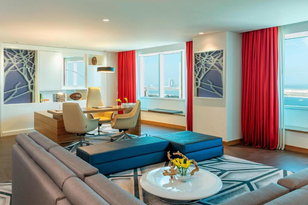 a living room with red curtains and a couch and a table at Le Royal Meridien Abu Dhabi in Abu Dhabi
