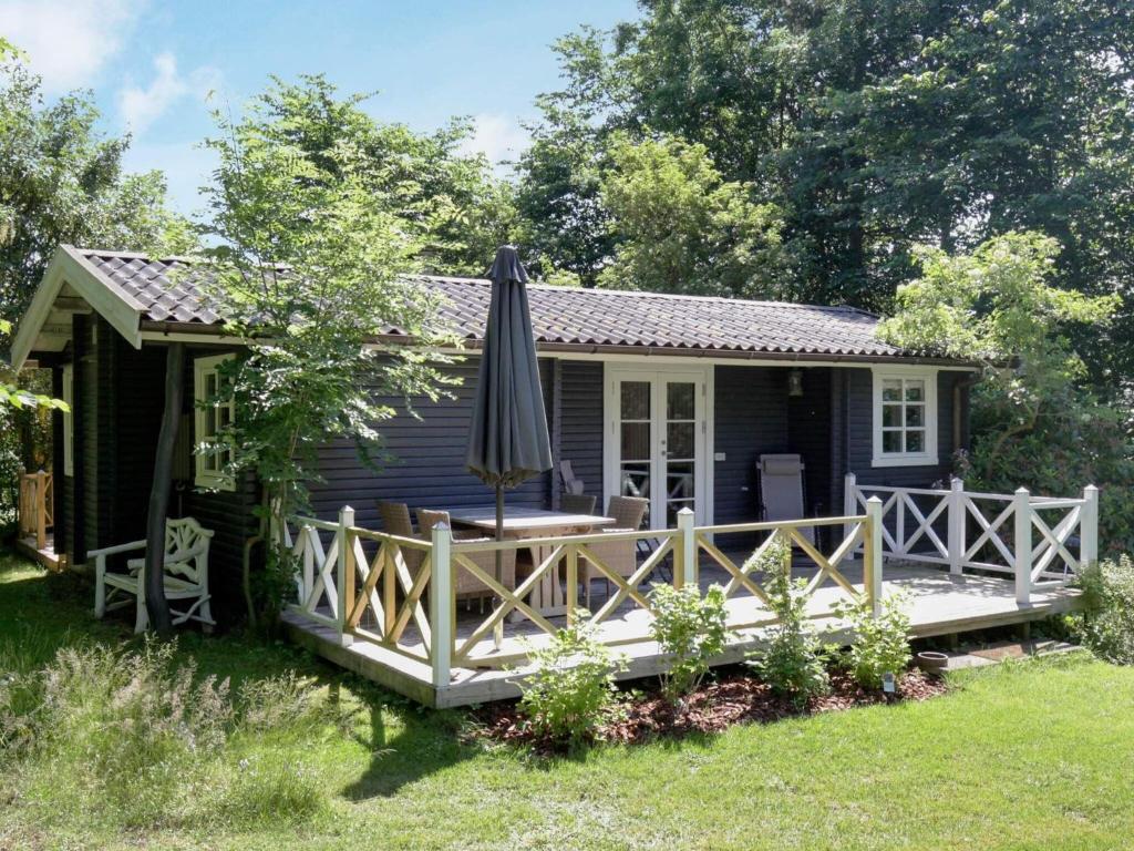 Ce cottage bleu comprend un parasol dans la cour. dans l'établissement Holiday Home Lindehøjen, à Vejby