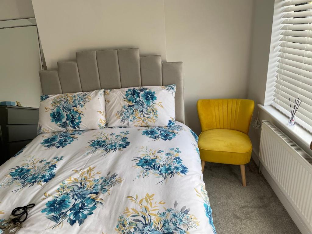 um quarto com uma cama e uma cadeira amarela em Warm welcoming Home em Manchester