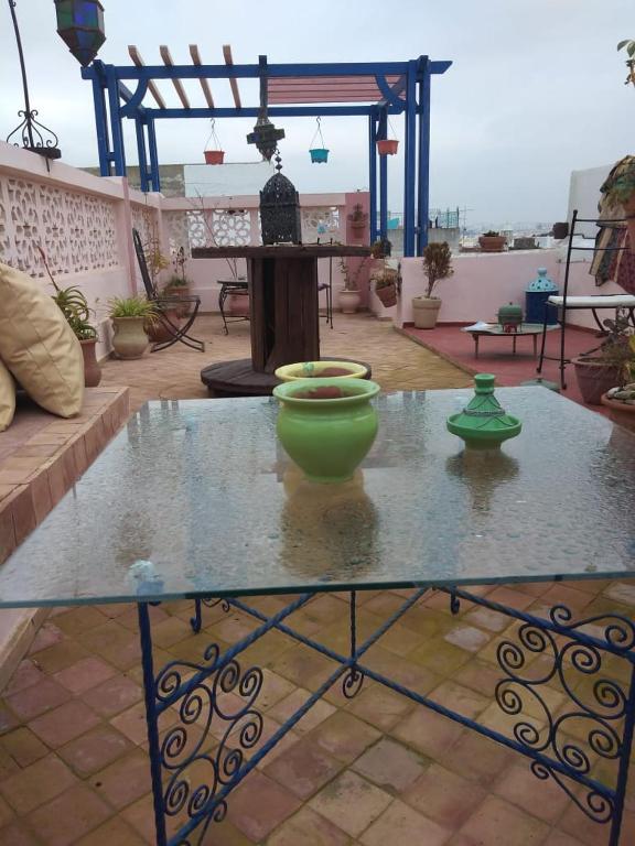 a glass table with two green vases on a patio at Dar Sam - Red Room in Rabat