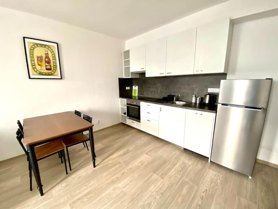 a kitchen with a table and a stainless steel refrigerator at Two-room apartment with garage in the center in Pilsen