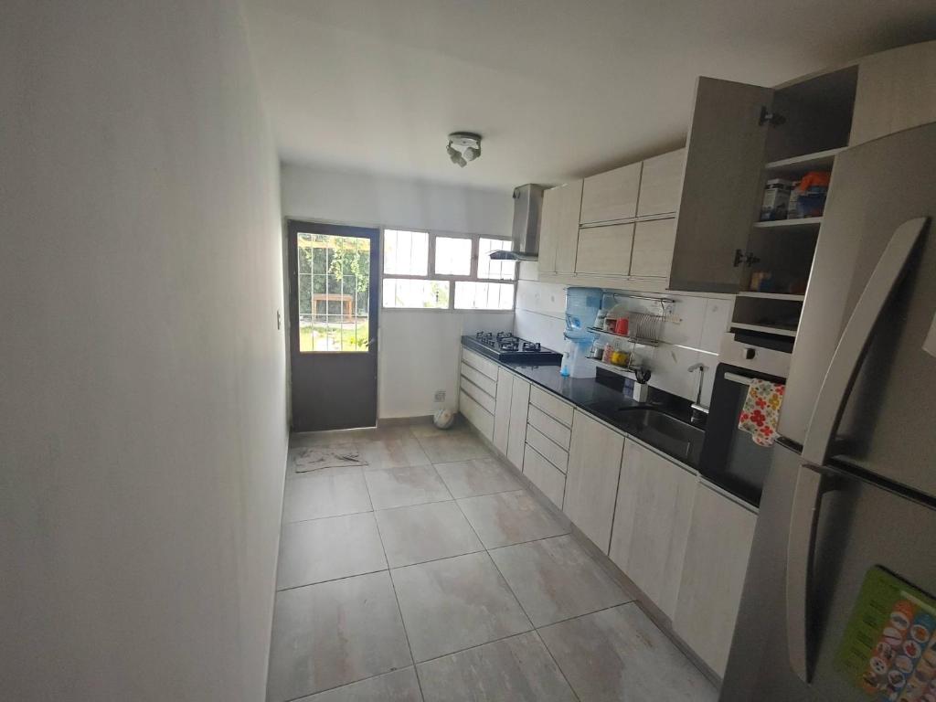 a kitchen with white cabinets and a tile floor at Casa familiar Rawson in Rawson