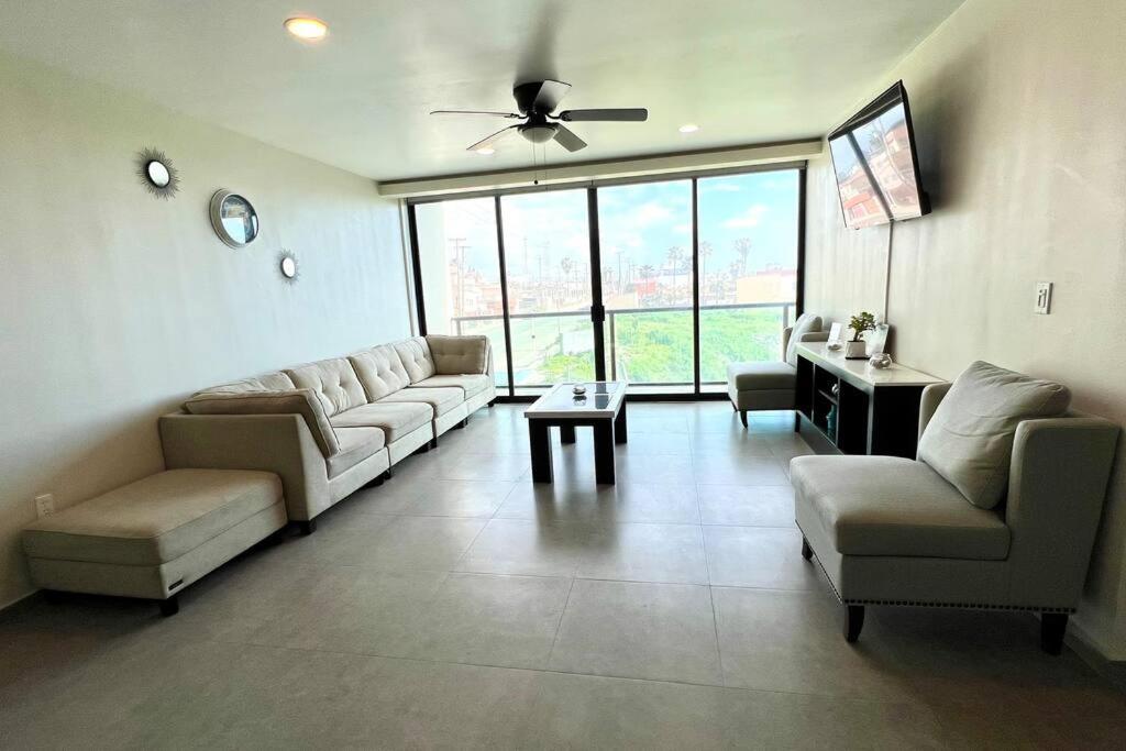 uma ampla sala de estar com sofás e uma ventoinha de tecto em Luxury 2BR Condo Rosarito (D) em Rosarito