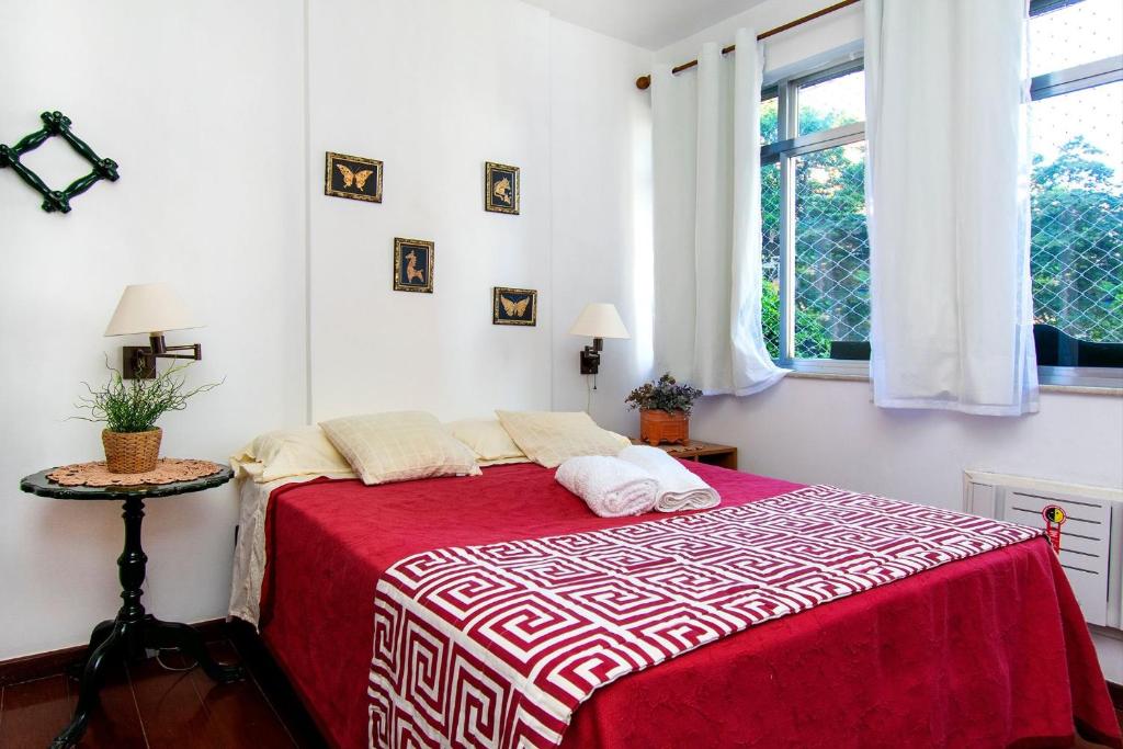 1 dormitorio con 1 cama con manta roja y blanca en Caminhe para a Praia de Ipanema e para a Rua Farme de Amoedo, 2 quartos, todo reformado, ar, WI FI, en Río de Janeiro