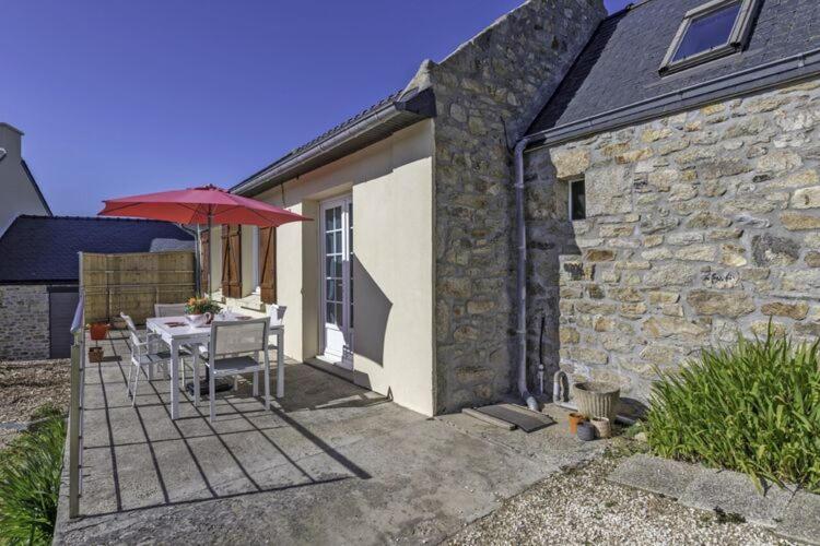 a table with an umbrella next to a stone building at Cottage in Plouarzel in Plouarzel