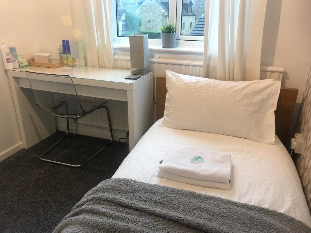 a bedroom with a bed with a desk and a window at fAiRy Dell Guesthouse with cozy lockable rooms, tv, free tea tray, free wifi, free parking in Oakenshaw