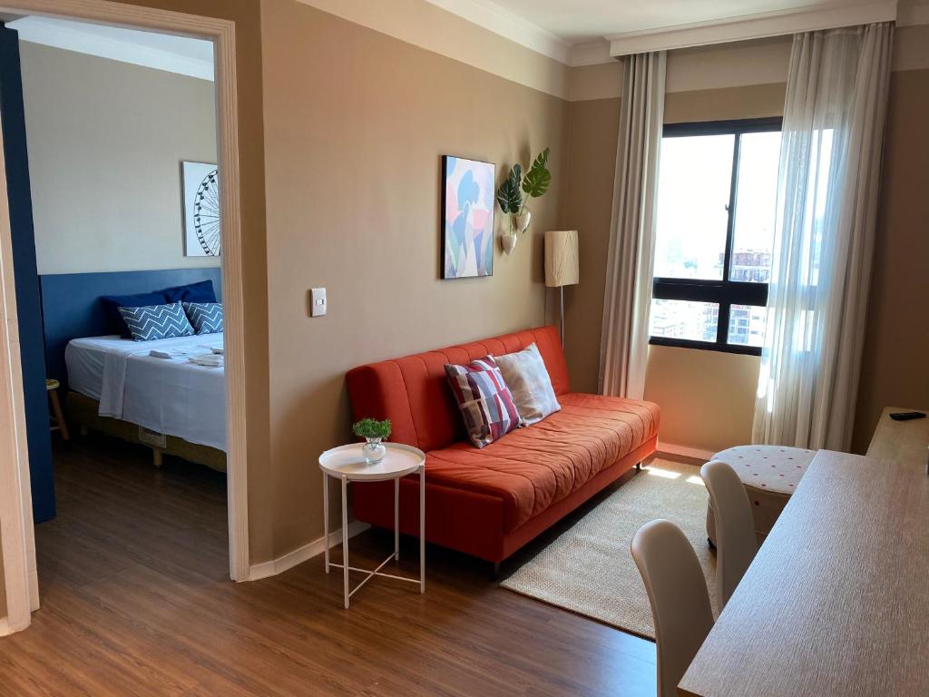 uma sala de estar com um sofá vermelho e uma cama em Comfort Flat Pinheiros em Hotel 4,5 estrelas em São Paulo