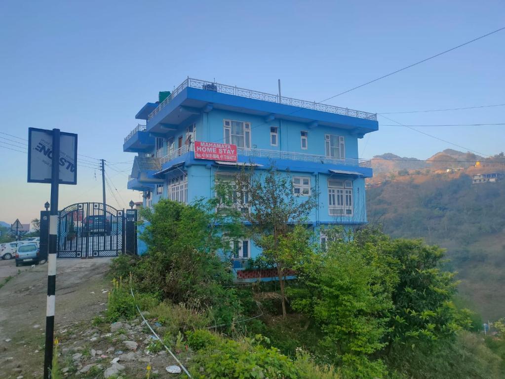 a blue building on the side of a hill at Mahamaya Homestay 4 in Mandi