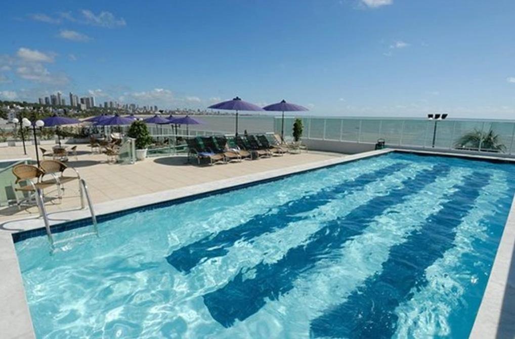 a large swimming pool with a view of the ocean at Blue Sunset in João Pessoa