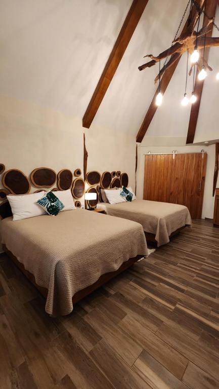 two beds in a room with wooden floors at Hotel Cabañas Aldea Maya in Xpujil