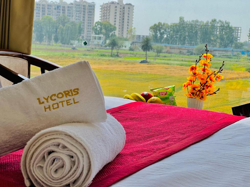 a towel on a bed with a view of a field at "Hotel The Lycoris" Near Bus Stand ZIRAKPUR on AMBALA HIGHWAY in Zirakpur