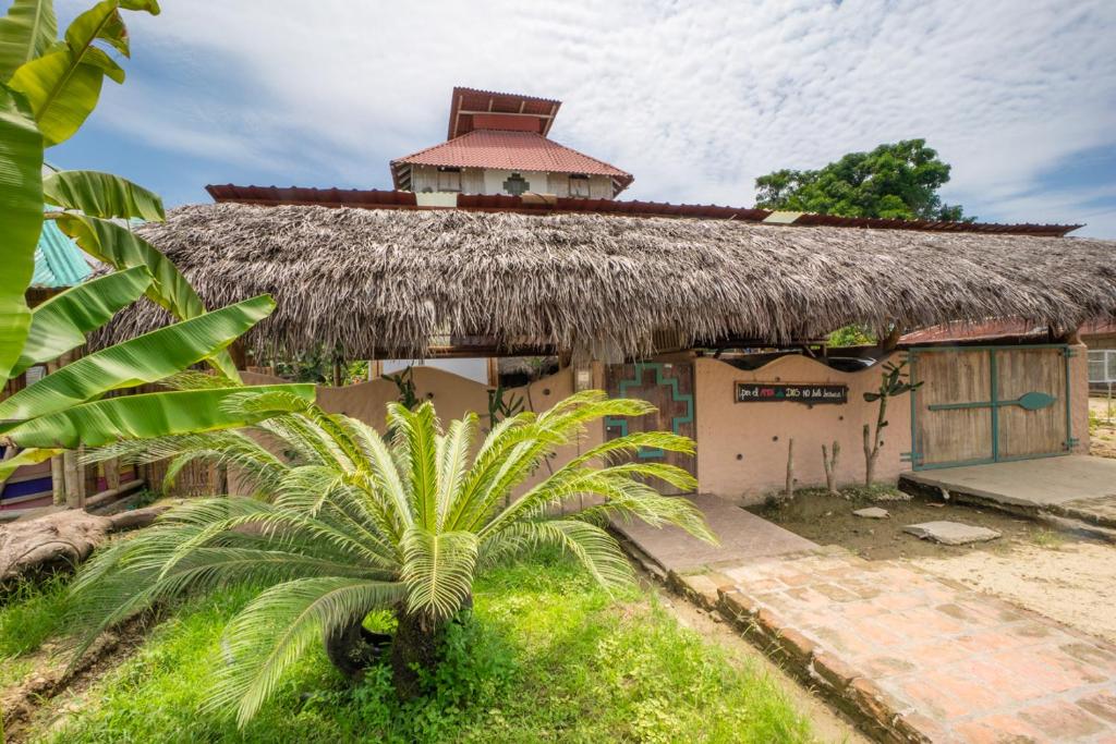 ein Gebäude mit einem Strohdach und einer Palme davor in der Unterkunft Paraiso Perdido in Mompiche