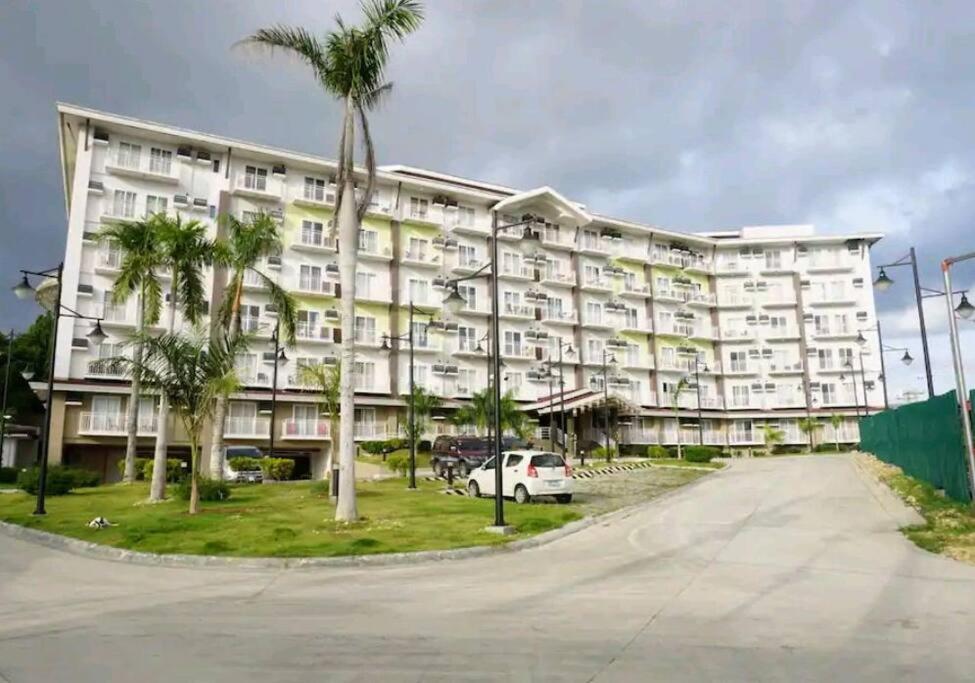 a large white building with palm trees in front of it at The Nearest Studio from MactanAirport with Disney+ in Pusok