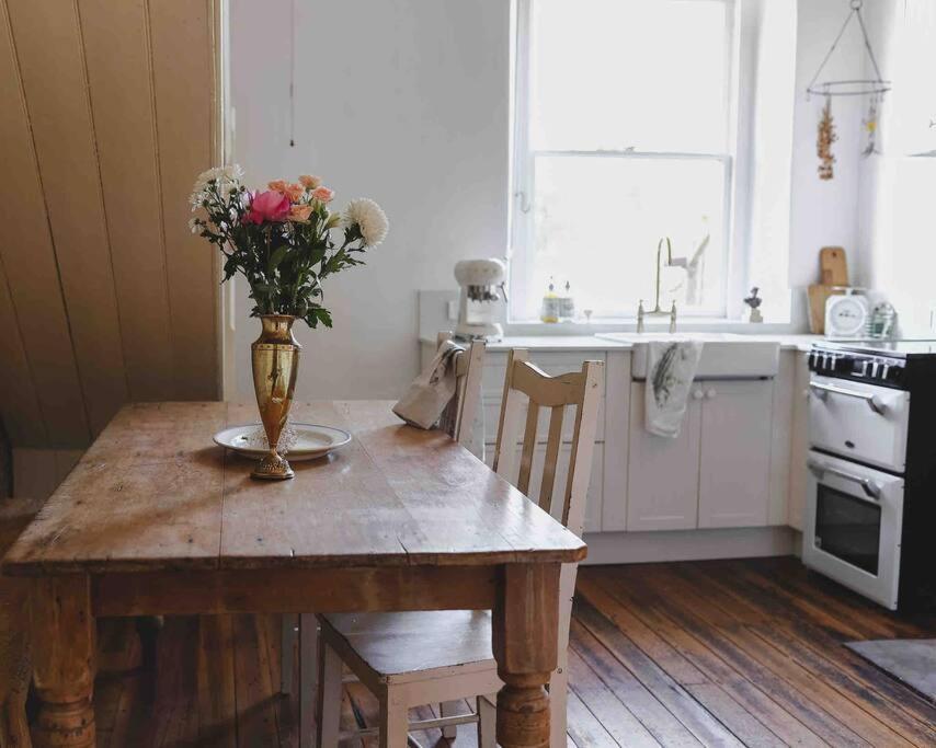 una cocina con una mesa de madera con un jarrón de flores. en The Shooters Cottage Bellerive I Circa 1830, en Bellerive