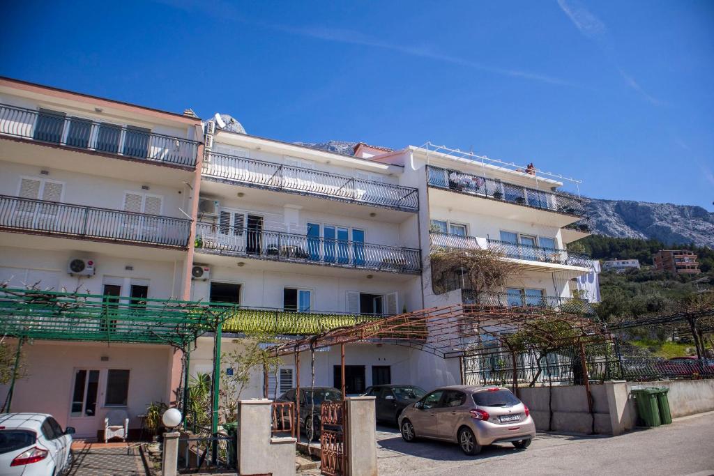 a large white building with cars parked in front of it at Apartments Julijana in Makarska