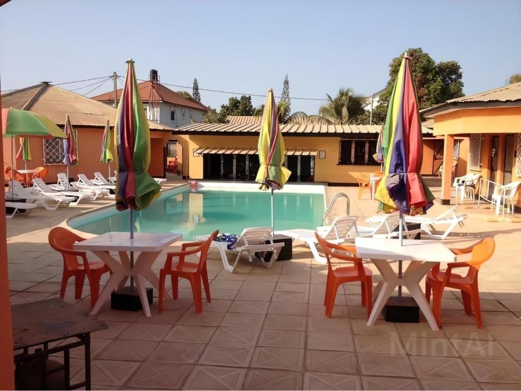 a group of tables and chairs with umbrellas next to a pool at Avalon Garden Lodge in Bathurst