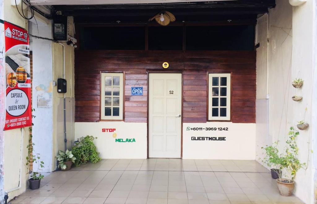 un edificio de madera con puerta blanca y 2 ventanas en Stop @Melaka Guesthouse en Melaka