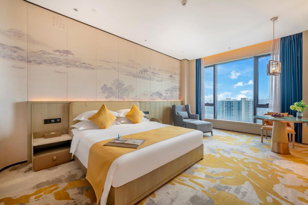 a hotel room with a large bed and a large window at Evwa Platinum Hotel in Huizhou