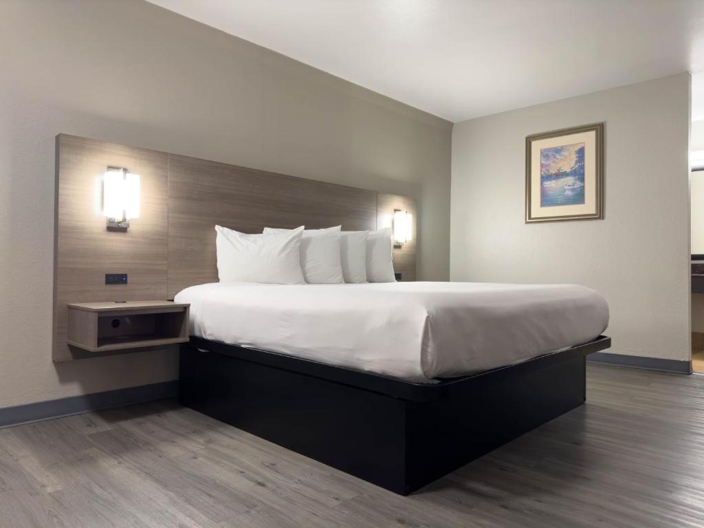 オースティンにあるアメリカズ ベスト バリュー イン オースティンのベッドルーム1室(大型ベッド1台、白いシーツ、枕付)