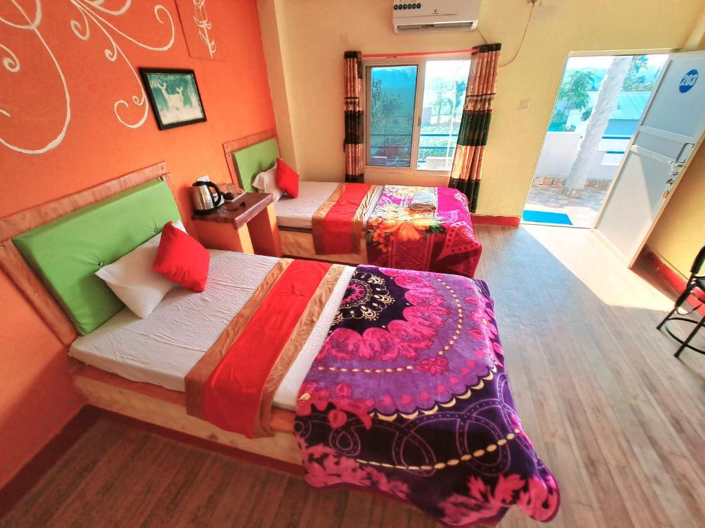 a bedroom with two beds with colorful sheets at Hong Qi Hotel in Chitwan