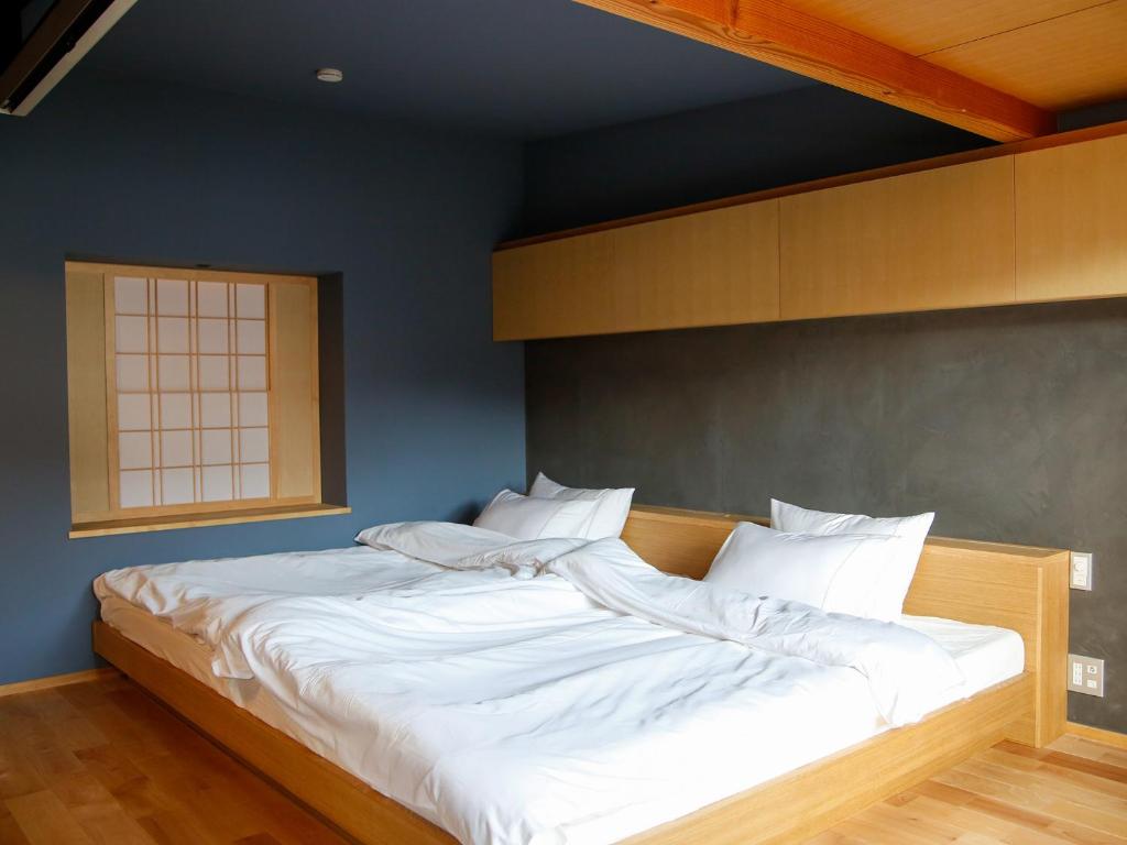 a bed with white sheets and pillows in a room at Temari Inn Madoromi in Kurashiki