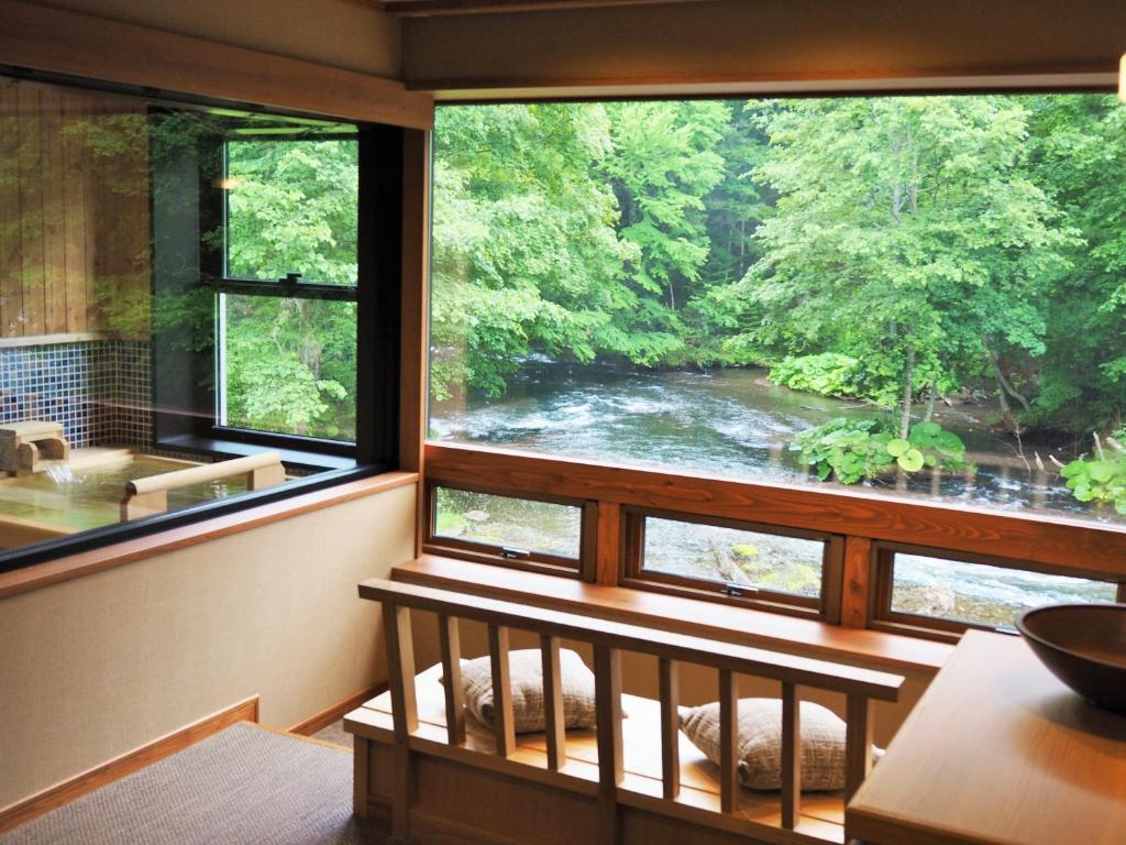 um quarto com uma grande janela com vista para um rio em La Vista Akangawa em Akankohan