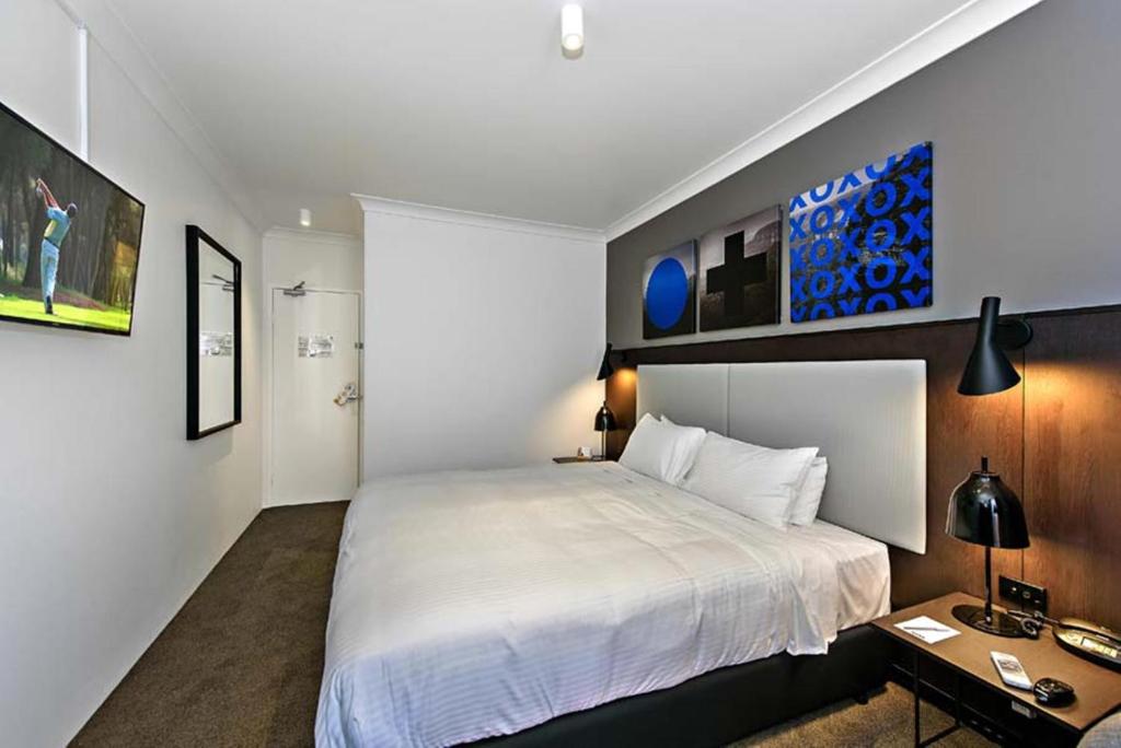 a bedroom with a large white bed and a desk at CKS Sydney Airport Hotel in Sydney