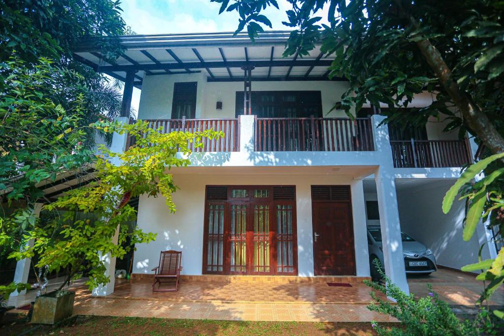 a white house with red doors and a balcony at Villa 382 in Galle