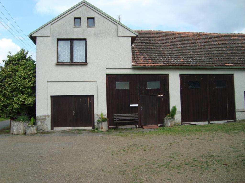 ein weißes Haus mit zwei Garagentüren und einer Bank in der Unterkunft Privát Mirovice-Březnice in Mirovice