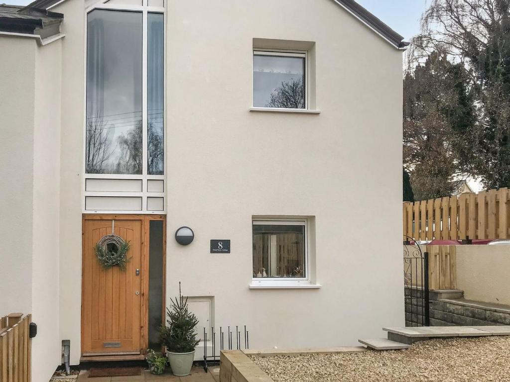 a white house with a wooden door at Clock Tower Cottage in Whitchurch