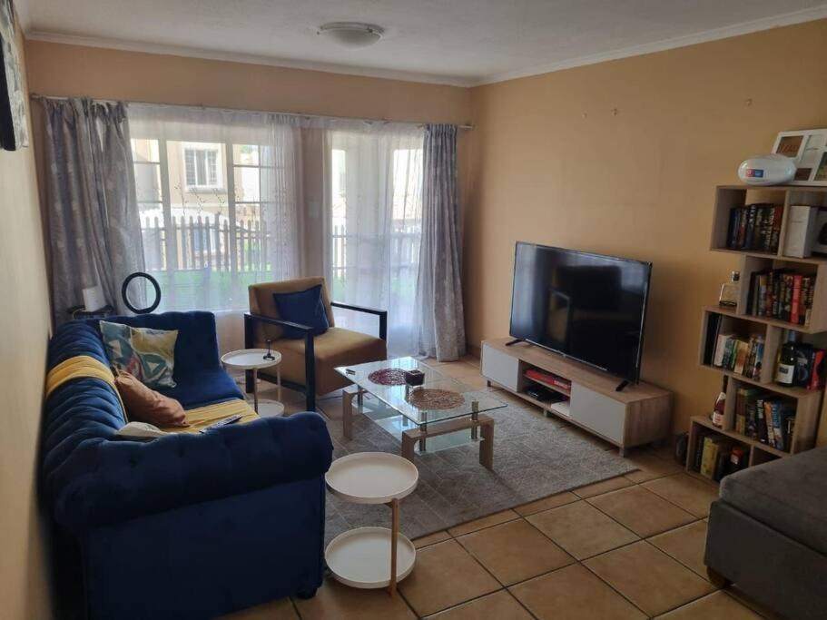 a living room with a blue couch and a tv at Self catering unit in Johannesburg
