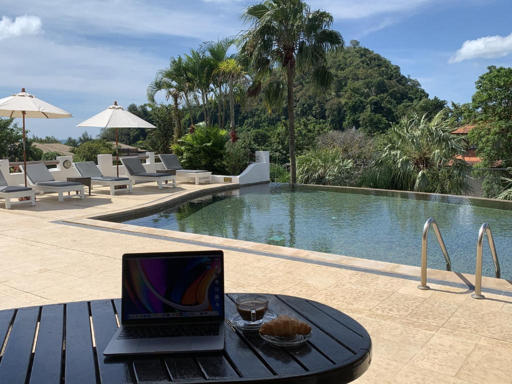 a laptop sitting on a table next to a swimming pool at Ao Nang Colors Hotel - Aonang Beach in Ao Nang Beach
