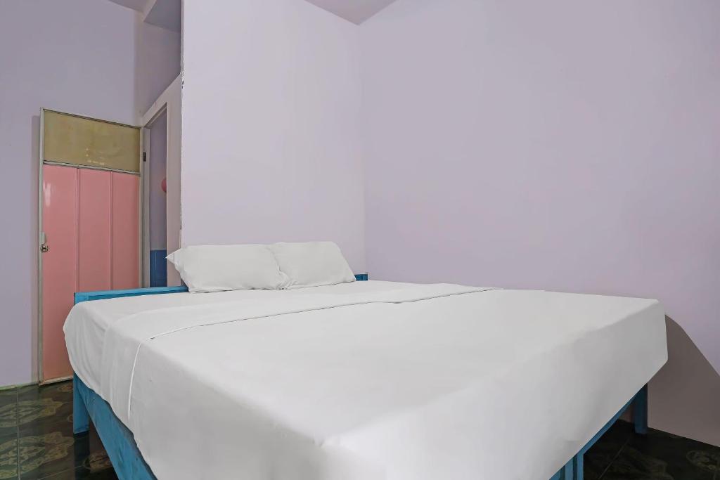 a large white bed in a room with a pink door at SPOT ON 92421 City Kost Syariah in Pangkal Pinang