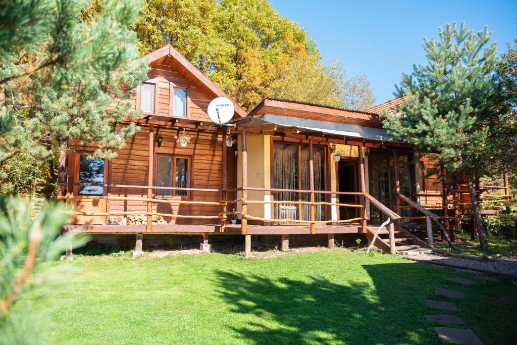 une maison en rondins avec une terrasse couverte et une cour dans l'établissement Forest House, à Zăbala