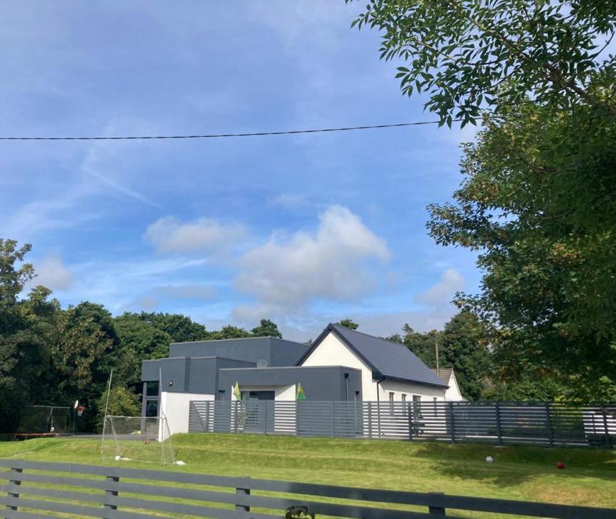 una casa bianca con una recinzione di fronte di Killarney modern family cottage a Killarney
