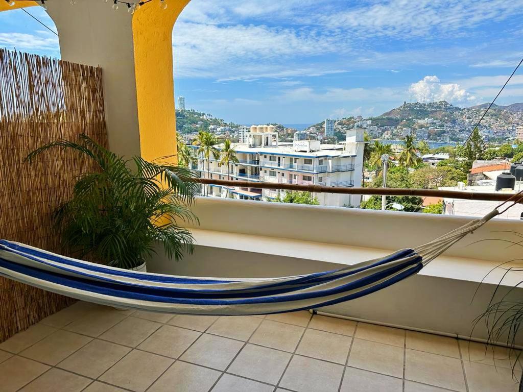 a hammock on a balcony with a view of a city at Twin Towers Tres Mares in Acapulco