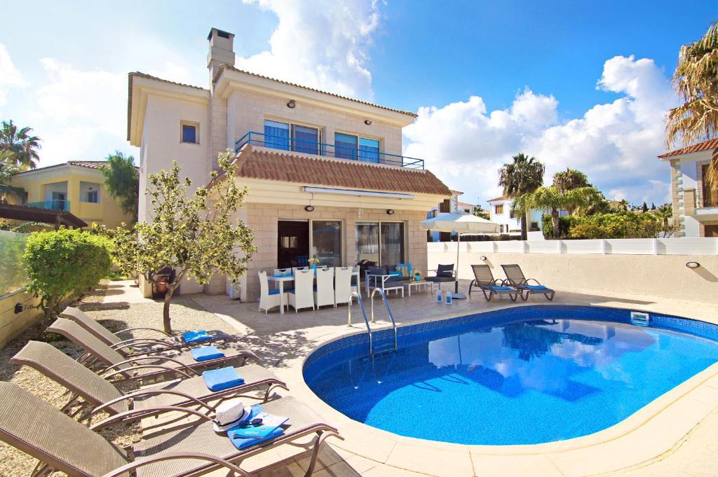 een zwembad met stoelen en een huis bij Villa Sonja in Protaras