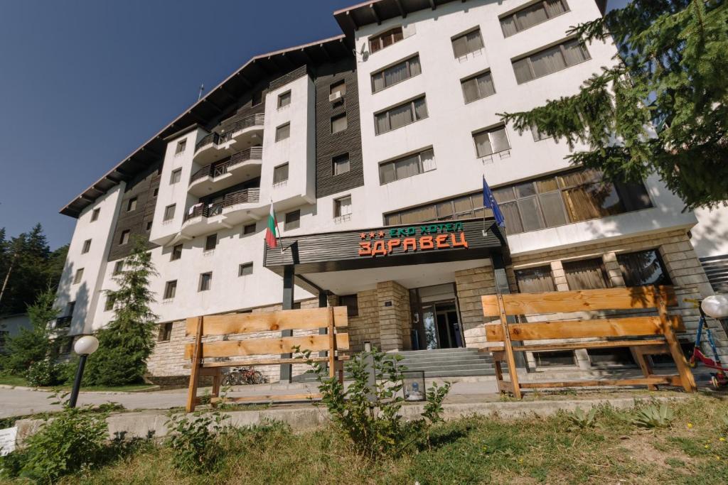 a building with two wooden benches in front of it at Eco Hotel Zdravetz in Tsar Kaloyan