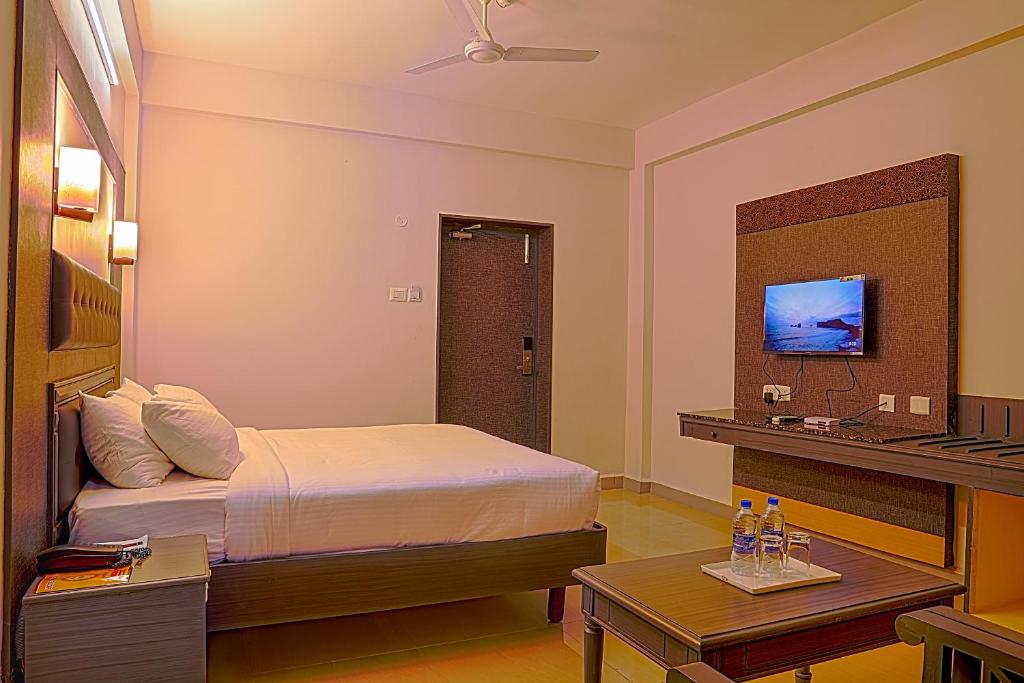 a bedroom with a bed and a desk and a television at Hotel Marvic in Tiruchchirāppalli