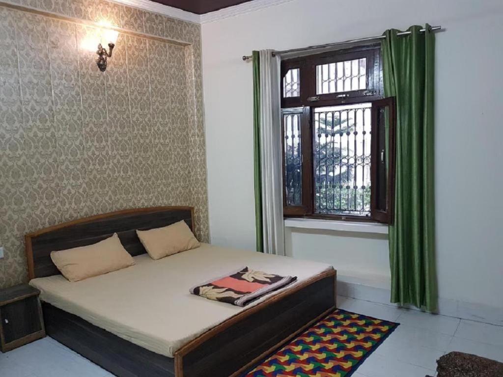 a bedroom with a bed and a window with green curtains at Sunrising Guest House Islamabad in Islamabad