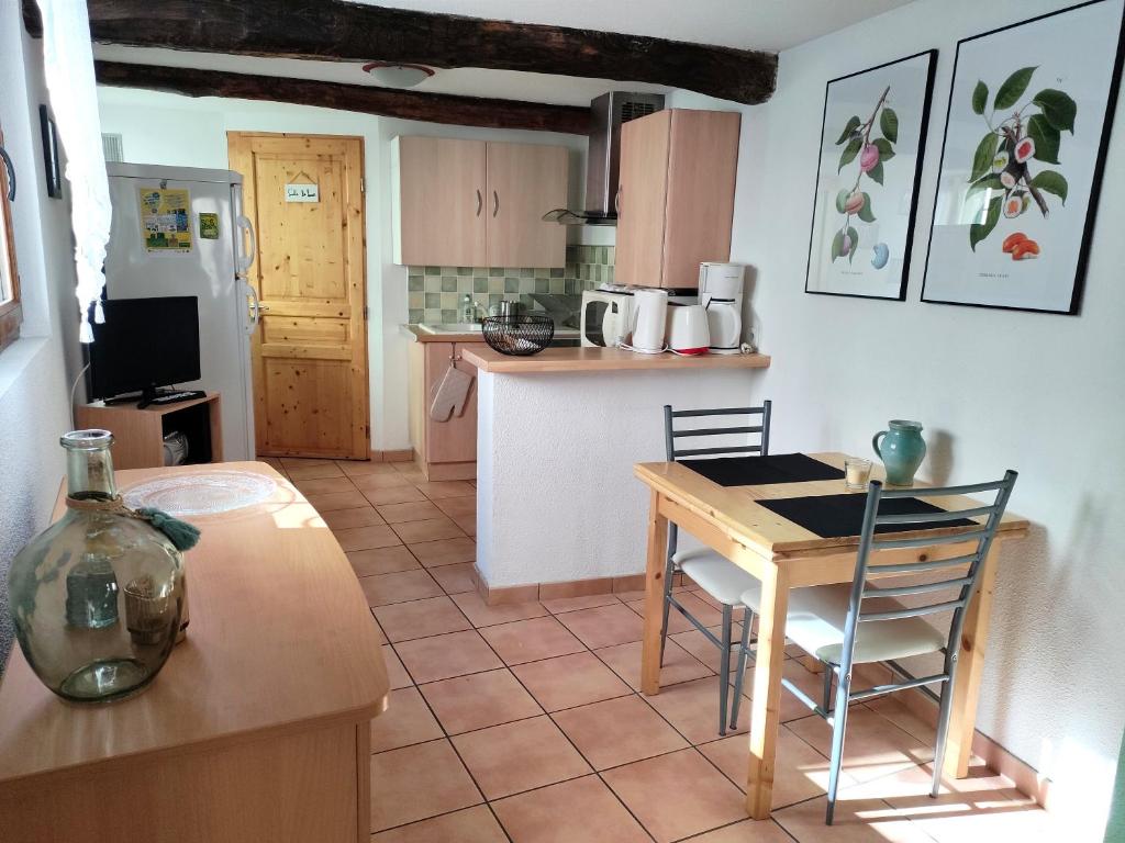 eine Küche mit einem Tisch, einem kleinen Tisch und Stühlen in der Unterkunft Confortable maison de village en pierre typique in Moltig les Bains