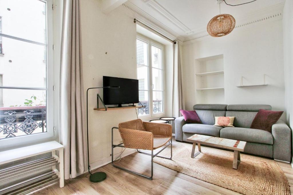 ein Wohnzimmer mit einem Sofa und einem TV in der Unterkunft Appartement Quartier Hotel de Ville in Paris