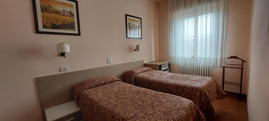 a hotel room with two beds and a window at Hotel Lea in Grosseto