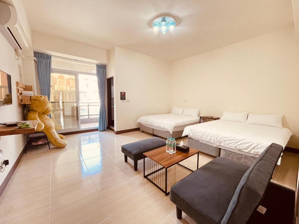 una sala de estar con 2 camas y un osito de peluche en Xinzhan 23 B&B, en Taitung