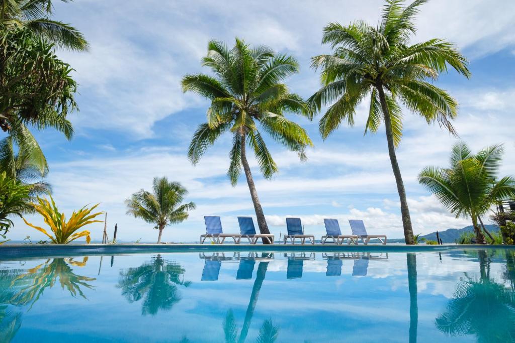 a swimming pool with palm trees and lounge chairs at Club Fiji Resort in Nadi