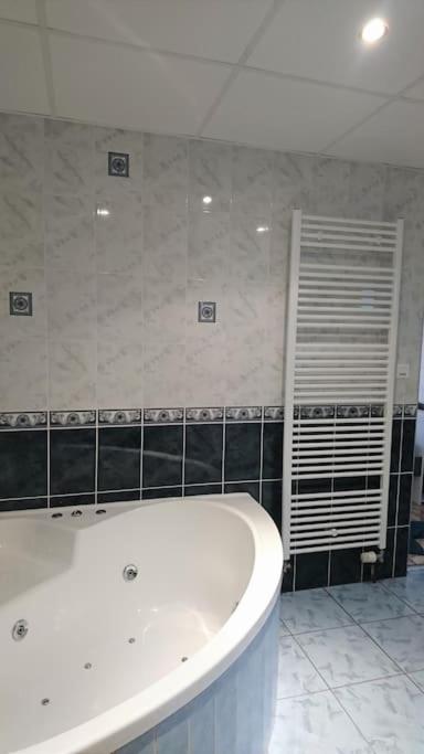 a white bath tub in a bathroom with black tiles at Au Coeur du Jura, Logement au calme in Champagnole