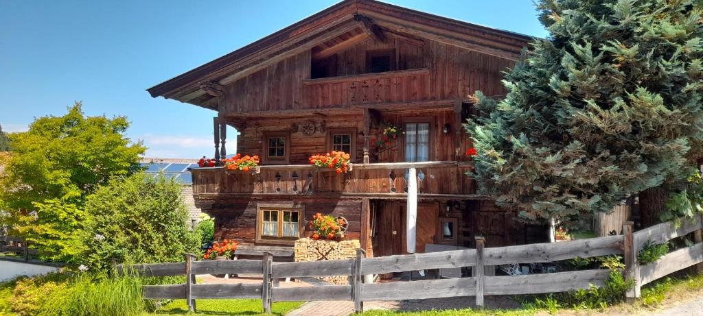 a wooden house with flowers in front of a fence at Holzfällerhaus Melkstatt in Auffach