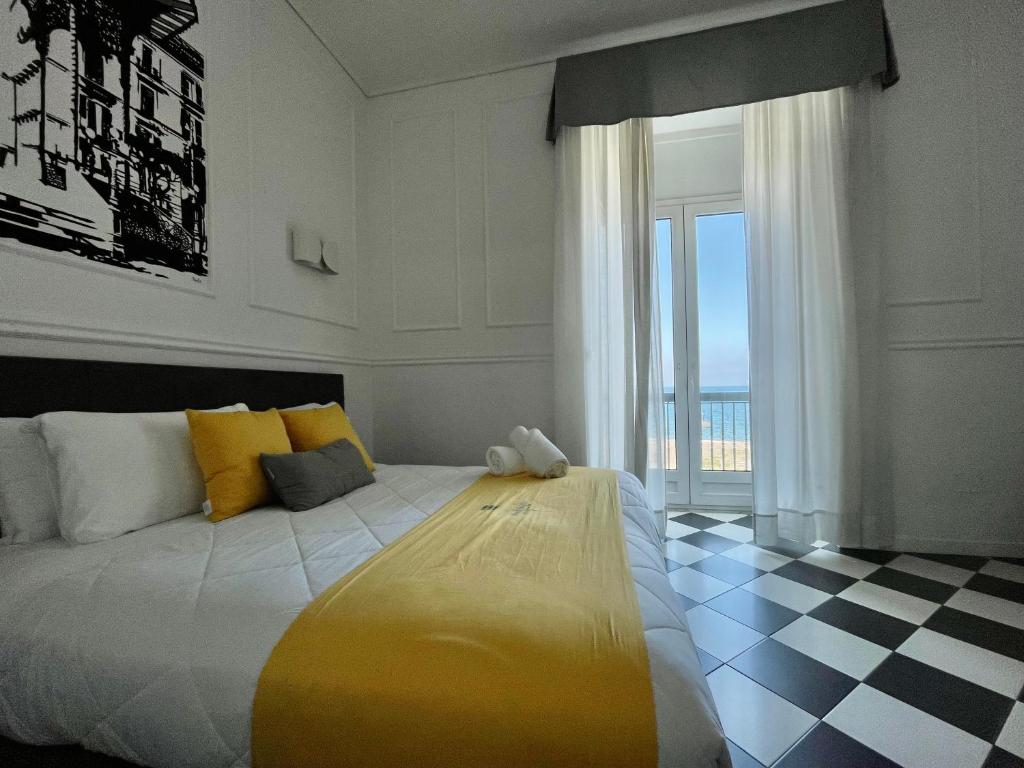 una camera da letto con un grande letto con una grande finestra di Hotel Stabia a Castellammare di Stabia