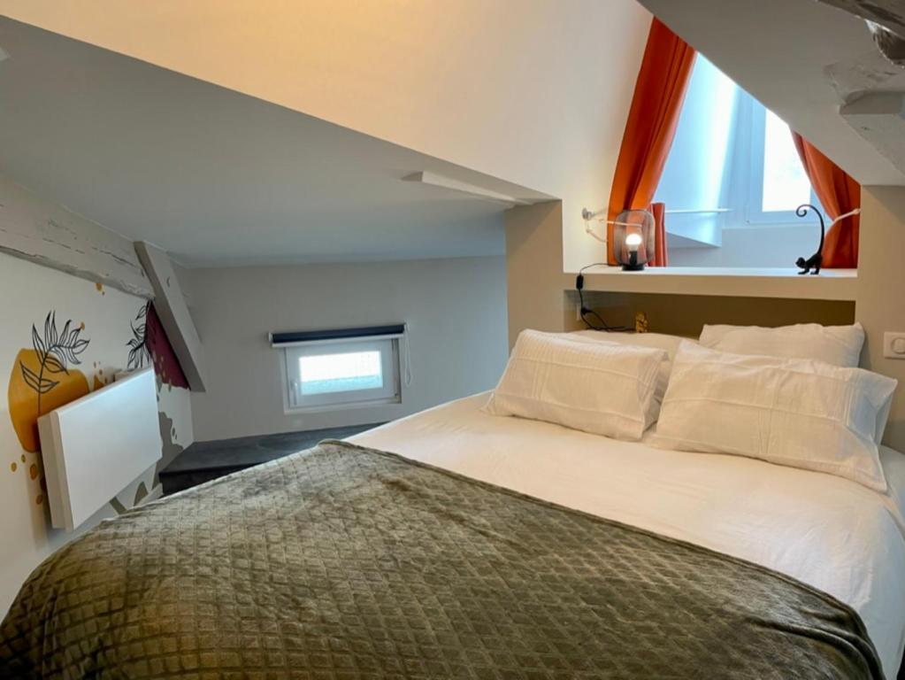 a bedroom with a large white bed and a window at Gîte les jasmins centre historique Saint-Astier in Saint-Astier